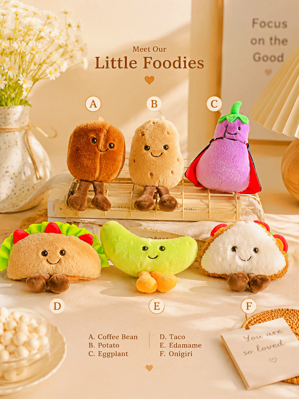 A set of six cute plush food-themed toys labeled A through F, arranged on a tabletop with decorative props. The plushies include a coffee bean, potato, eggplant, taco, banana, and onigiri.