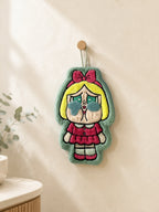 Cute mint green character hand towel hanging from a wooden wall peg in a warm minimalist bathroom