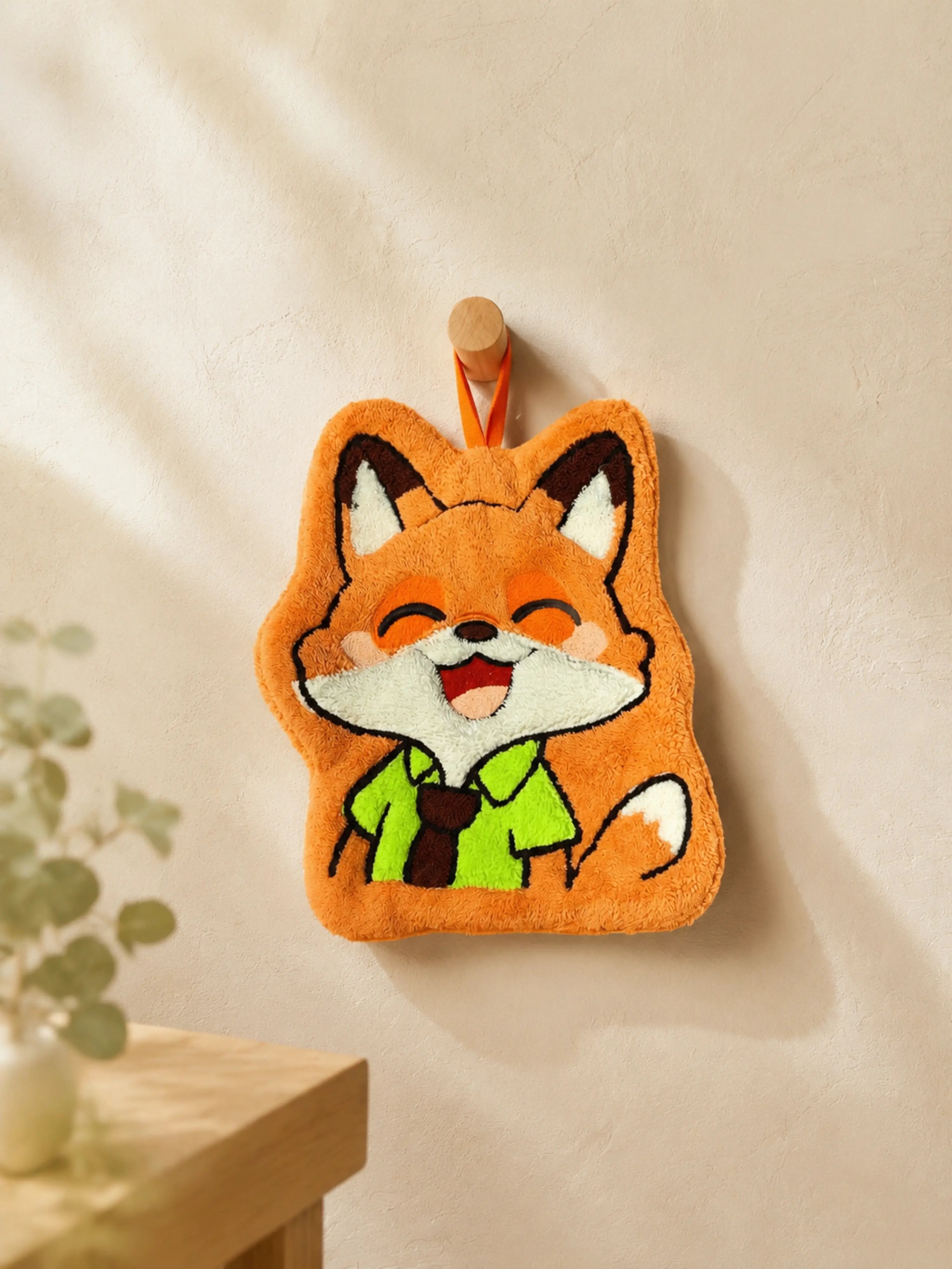 Cute orange fox character hand towel hanging from a wooden wall peg in a warm minimalist bathroom