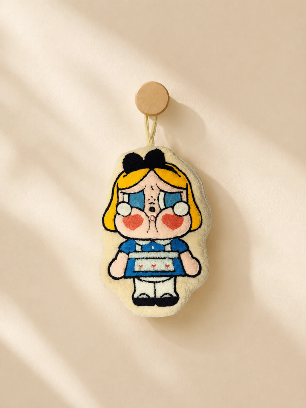 Cute cream and blue character hand towel hanging from a wooden wall peg in a warm minimalist bathroom