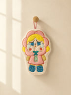 Cute pink flower hood character hand towel hanging from a wooden wall peg in a warm minimalist bathroom